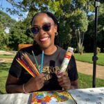 Woman smiling while holding the Mindful Coloring Set with affirmations coloring book and colored pencils