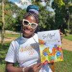 Smiling woman holding coloring book close to chest