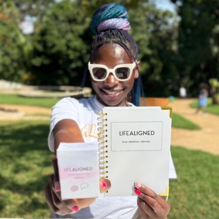 Smiling woman holding Grey Life Aligned Planner outdoors