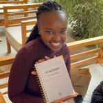 Woman holding grey Life Aligned Planner with a smile