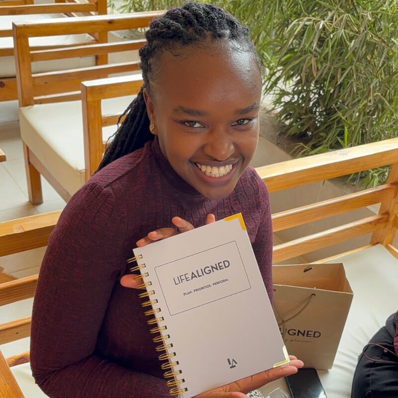 Woman holding grey Life Aligned Planner with a smile